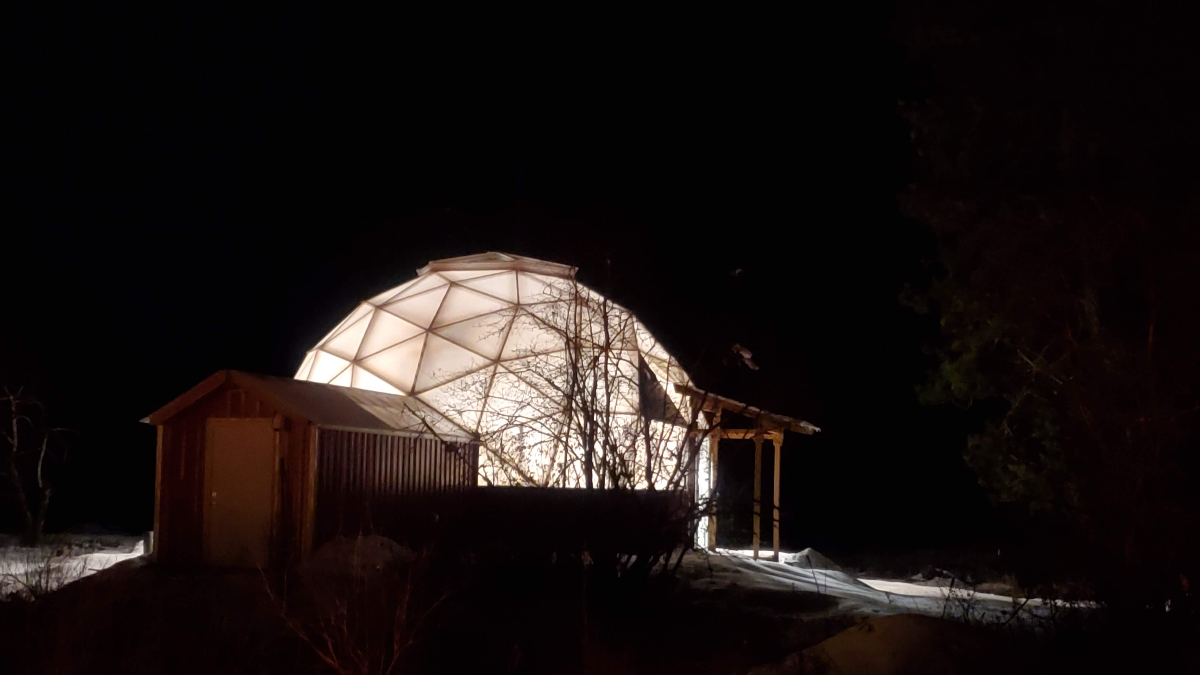 The greenhouse dome glowing against deep snow on a winter night